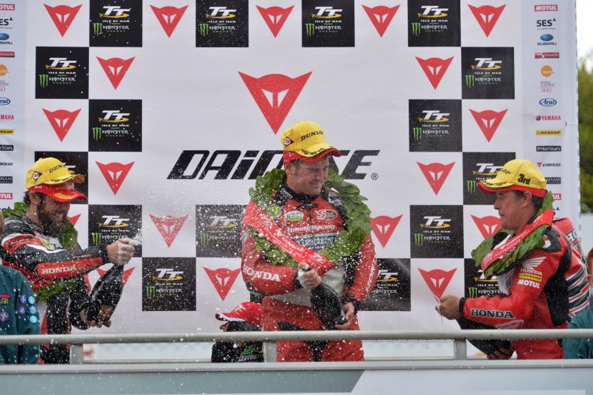 Dunlop gets showered in Champagne by John McGuinness (3rd). Also pictured is 2nd place Cameron Donald